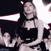 a woman in a black dress is sitting in front of a group of people