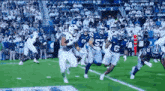 a football game is being played on a field with players in white and blue uniforms .
