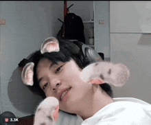 a young man wearing headphones has a sticker on his face that says 3.3k on it