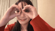 a woman in a red sweater is making a heart with her hands