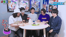 a group of men are sitting around a table and one of them is wearing a purple xlarge shirt