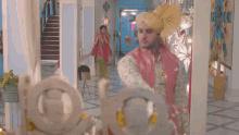 a man wearing a turban and a pink jacket is standing in front of a mirror .