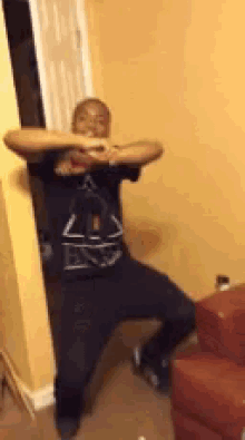 a man is dancing in a living room next to a red chair .