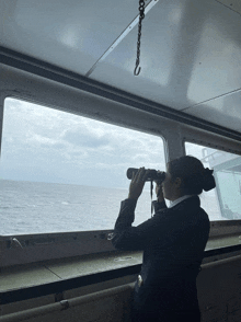 a woman is looking through binoculars on a boat