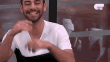 a man with a beard wearing a white shirt is laughing with his eyes closed .