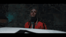 a man with dreadlocks is standing next to a white car .