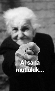 a black and white photo of an elderly woman pointing her finger at the camera .