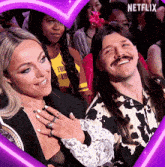 a man and woman are posing for a picture in front of a heart with netflix written on it