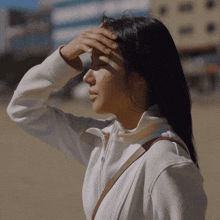 a woman wearing a white jacket is covering her eyes with her hand