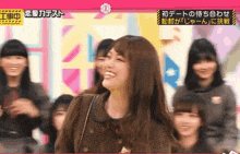 a woman is smiling in front of a group of girls on a tv show .