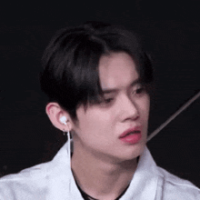 a close up of a young man wearing a white shirt and earrings .