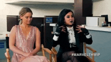 two women are sitting next to each other in chairs in a room .