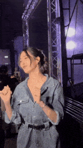 a woman in a denim jumpsuit is dancing in front of a crowd .