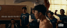 a group of young men are standing around a man in a shirt that says kahar