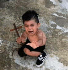 a baby is crying while holding a cross in his hands .