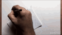 a hand is drawing on a piece of paper with the words made in animatica visible