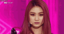 a woman with red hair is standing in front of a pink curtain and a microphone .