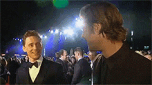 two men in tuxedos are standing next to each other on a red carpet