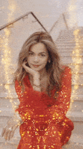 a woman in a red dress sits on stairs with her hand on her chin