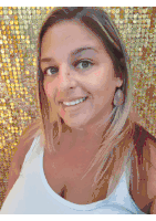 a woman wearing a white tank top and earrings is smiling