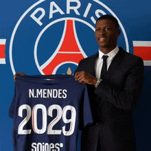a man in a suit holds up a shirt that says 2029