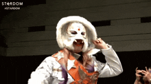 a woman wearing a white mask is standing in front of a stardom sign