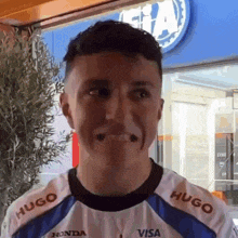a man wearing a hugo visa shirt makes a face