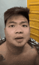 a shirtless man with a tattoo on his chest is making a funny face in front of a yellow dresser