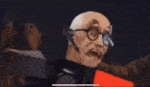 a bald man wearing glasses and a headset stands in front of a computer monitor