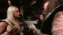 a man with a tattoo on his arm is standing next to two women