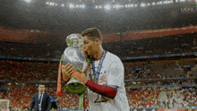 a soccer player kisses a trophy with the uefa logo in the background