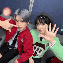 two young men are posing for a picture and one of them is wearing a green sweater and the other is wearing a red jacket and tie