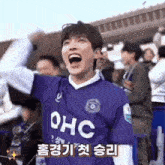 a man wearing a purple shirt that says ohc is cheering