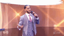 a man in a suit and tie is standing in front of a microphone on a stage .