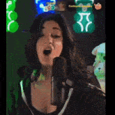 a woman is singing into a microphone with a green background