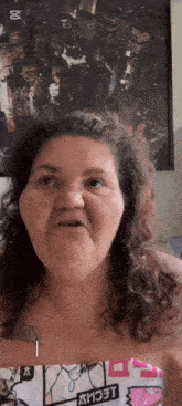 a woman with curly hair is making a funny face in front of a framed picture of a city