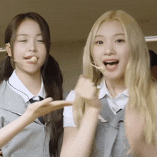 two girls in school uniforms are making funny faces and one has a microphone in her mouth