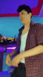 a man in a plaid shirt is dancing in a room with a purple wall .