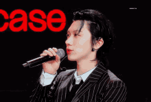 a man in a suit singing into a microphone in front of a red case sign