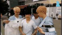 a group of young men are standing next to each other holding a shirt .