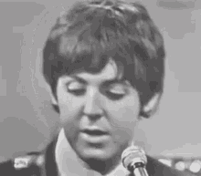 a black and white photo of paul mccartney singing into a microphone .