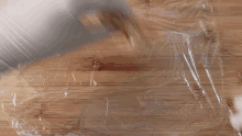 a person wearing a white glove is wrapping a piece of food in plastic wrap