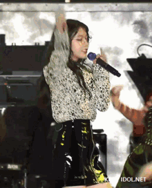 a girl singing into a microphone with idol.net written on the bottom right
