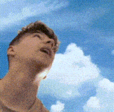 a man is looking up at a blue sky with white clouds .