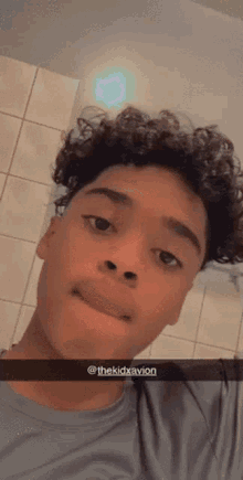 a young man with curly hair is taking a selfie with his phone .