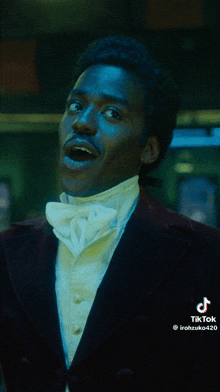 a man in a tuxedo with a white bow tie is smiling