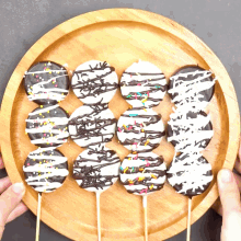 a person is holding a wooden plate with chocolate covered cookies and sprinkles on them