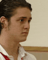 a close up of a man 's face with a white shirt and a red tie