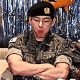 a man in a military uniform with his arms crossed is sitting on a couch .
