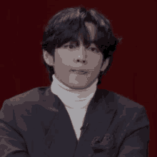 a close up of a person wearing a suit and a turtleneck .